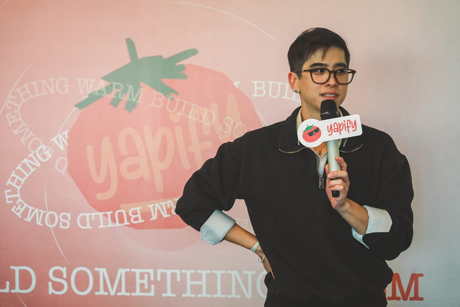 Our MC on stage with the microphone in front of the Yapify tomato backdrop